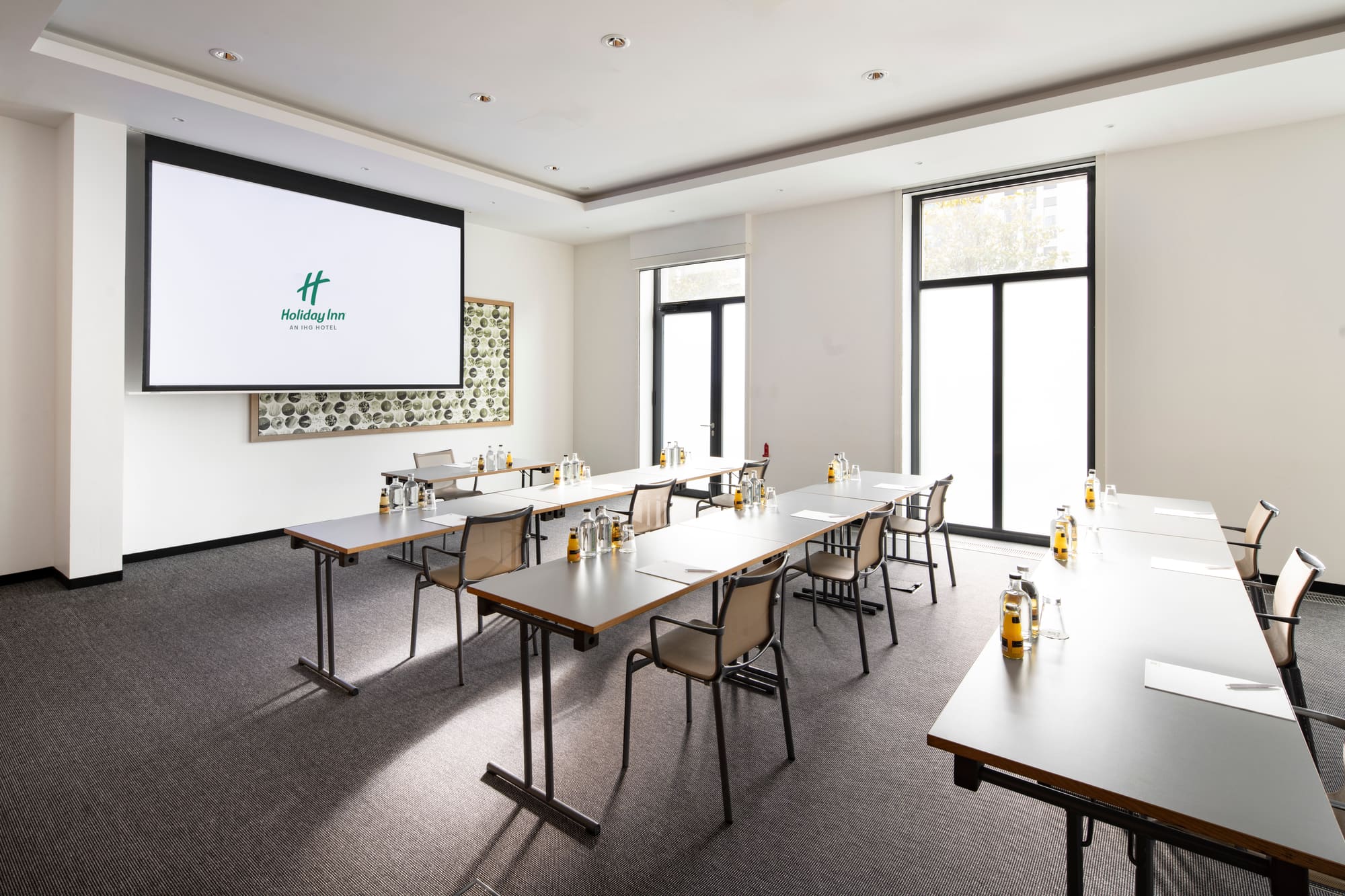 A daylight meeting room at Holiday Inn Frankfurt - Alte Oper with a built-in screen and projector, seating up to 90 people theatre style.